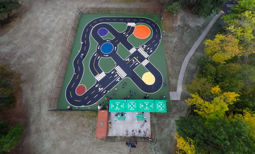 aerial view of miniature streets and traffic circles painted onto asphalt surface.