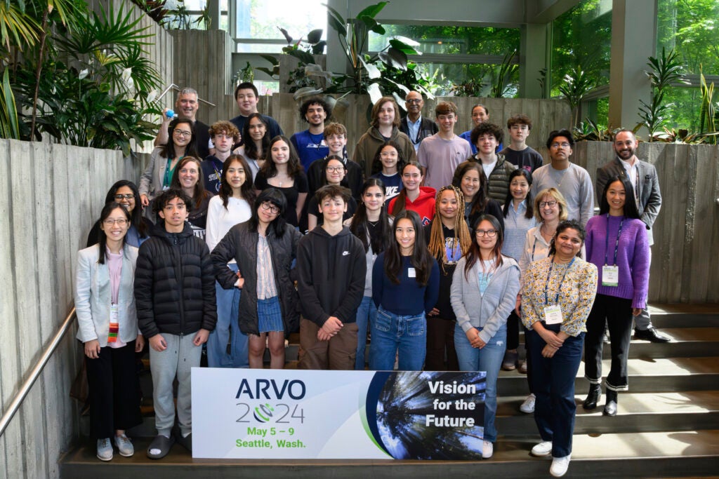 Group of students posing in front of ARVO conference poster