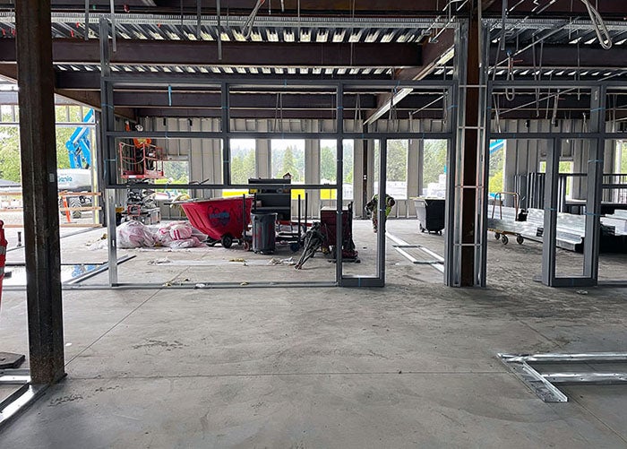 inside a partially built building with steel framing for walls being installed on a concrete floor