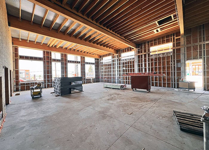 a large room under construction with metal framed walls and wood framed ceiling with piping