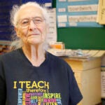 Marletta Iwasyk sits in her classroom, smiles at camera