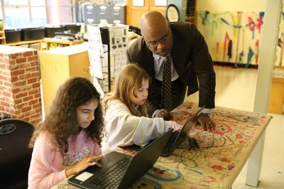 Superintendent Dr. Jones asking students about their work, students showing their work on a laptop