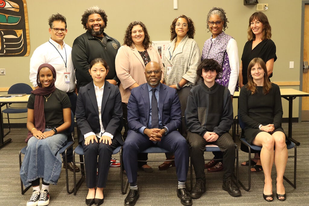 A group of 11 people gather for a photo in the SPS auditorium