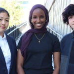 The three student board members pose for a photo outside.