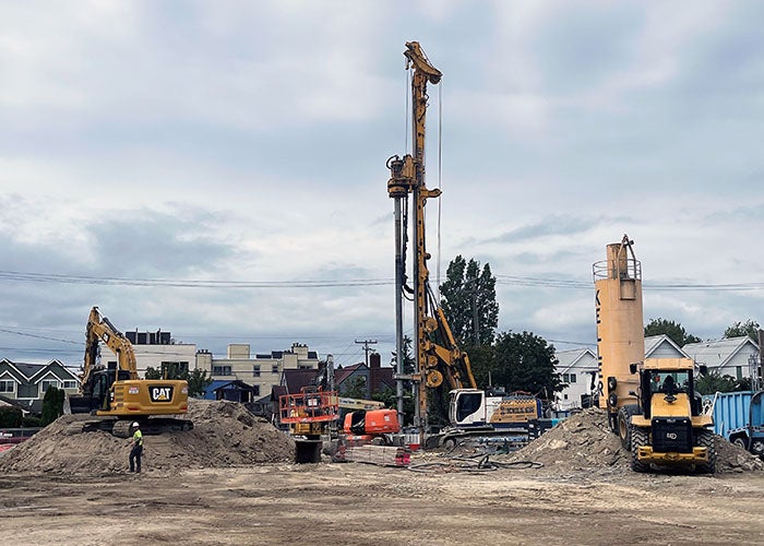 a grader, drill rig, and other construction equipment in a dirt construction site