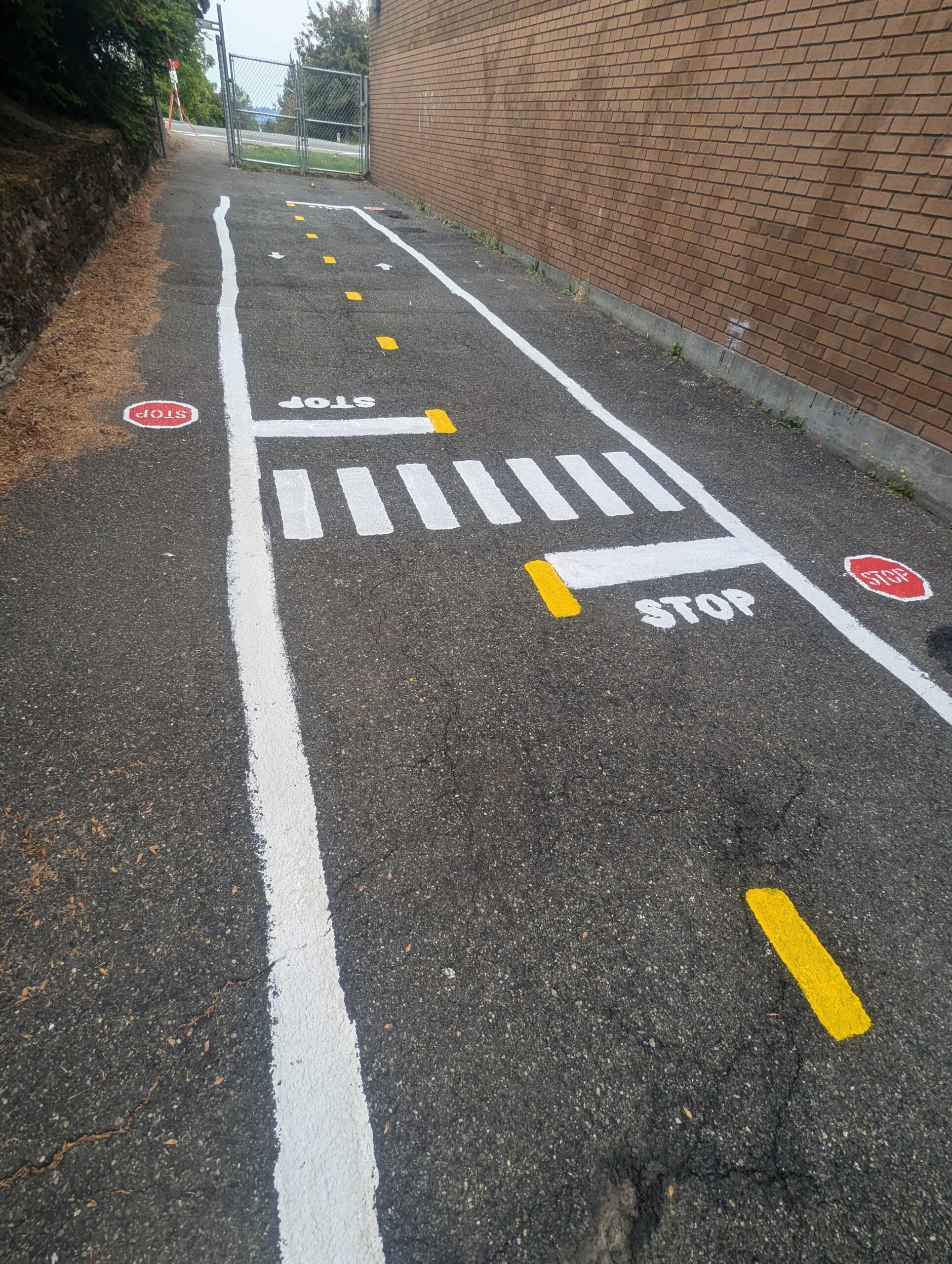 Miniature pedestrian crosswalk and stop signs on traffic garden roadway.