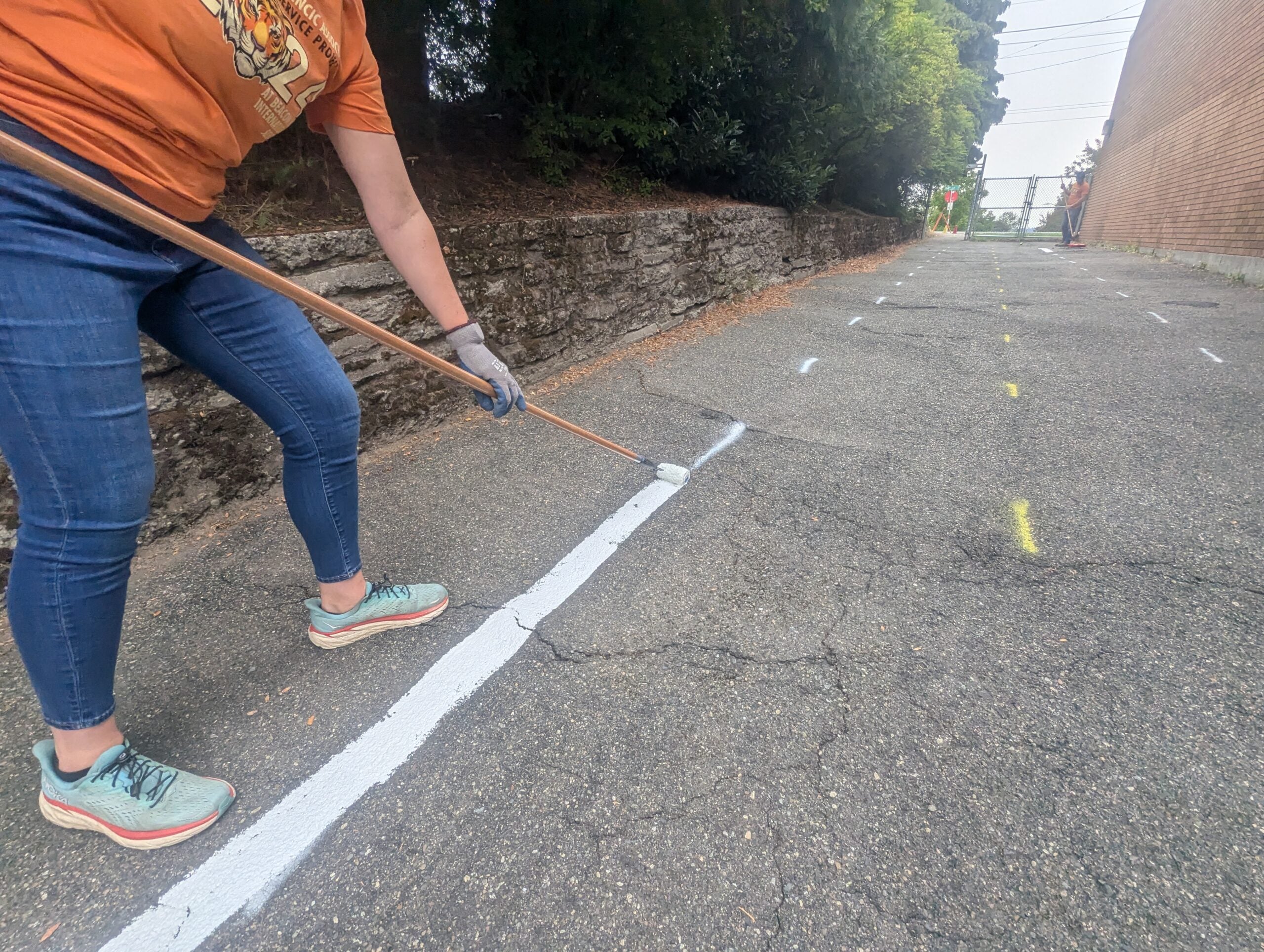 Volunteer painting street line for miniature traffic garden street.