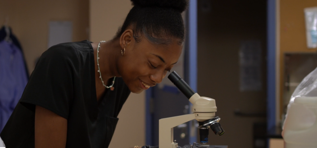 Student laughing at microscope