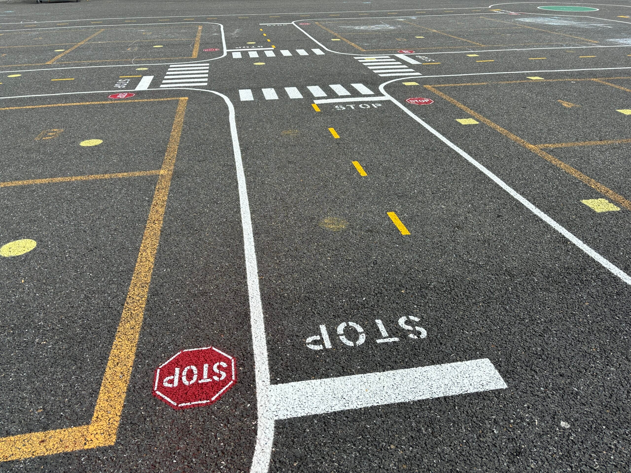 Miniature road painted on blacktop with stop sign.