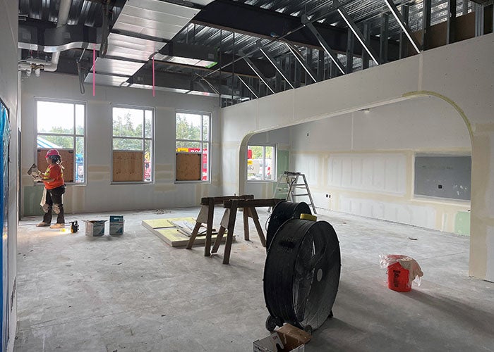 a partially finished room under construction with a person working on wallboard