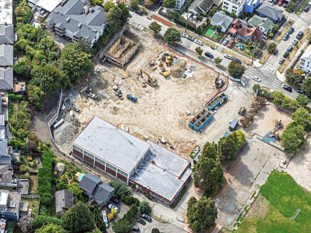 aerial of a construction site that is about a full block. there is a building on one side