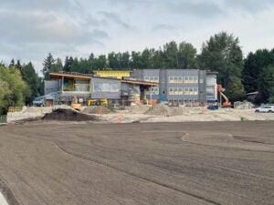 a large building under construction with a field of soil in front