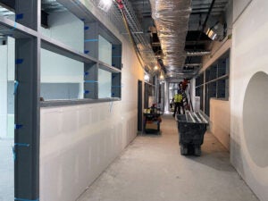 a hallway under construction with the ceiling open showing wiring and ducting