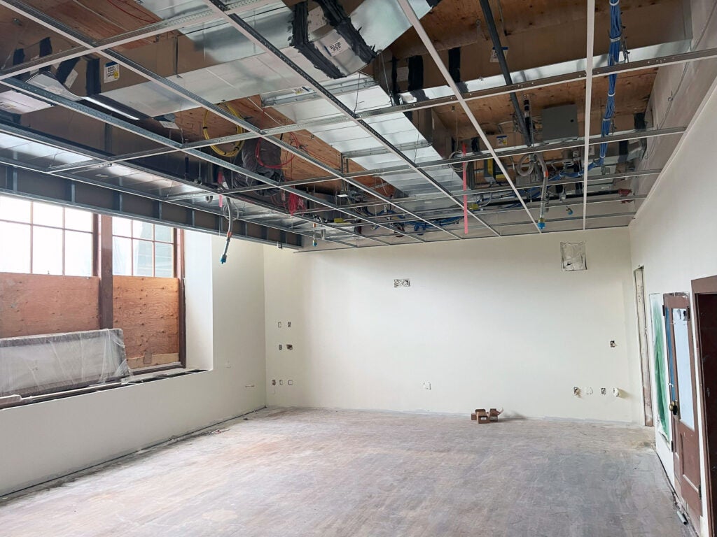 a large room with a ceiling grid and partially covered windows