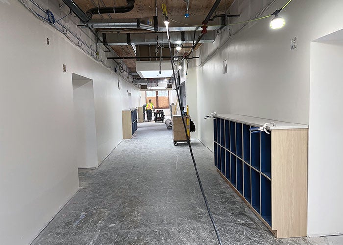 a wide hallway with an open ceiling and work lights