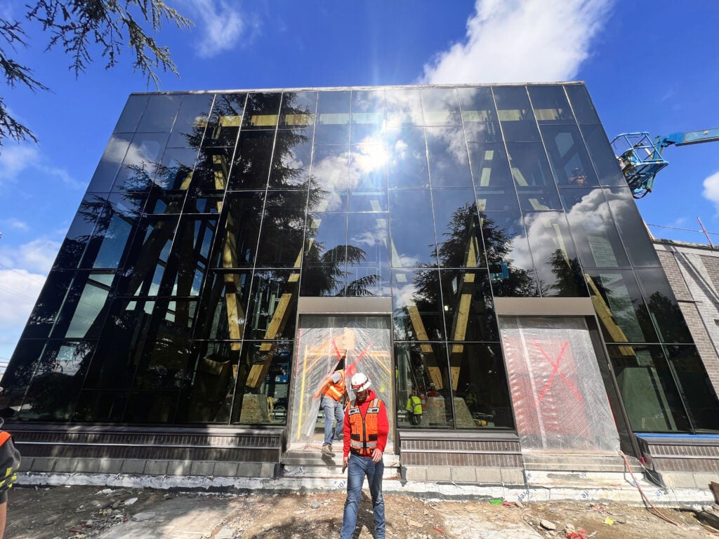 a two story glass wall exterior with holes for doorways covered in plastic