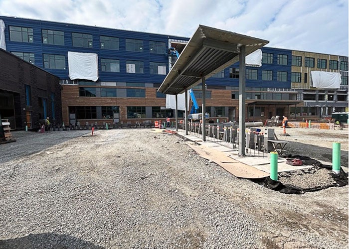 exterior of a building under construction with a canopy being installed in the middle of a gravel lot