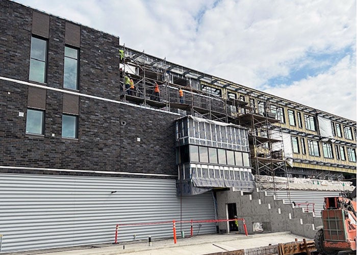 a building under construction with people working on a scafforld on the third level