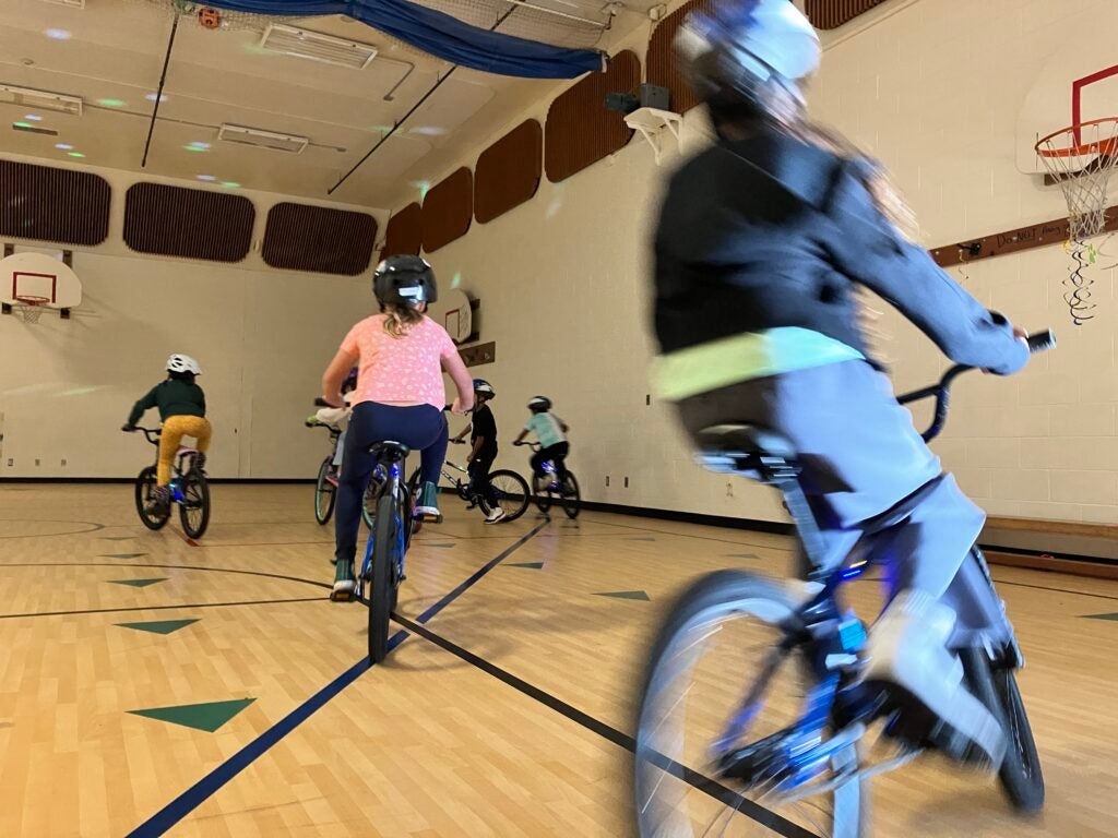 Students ride bikes in gym.