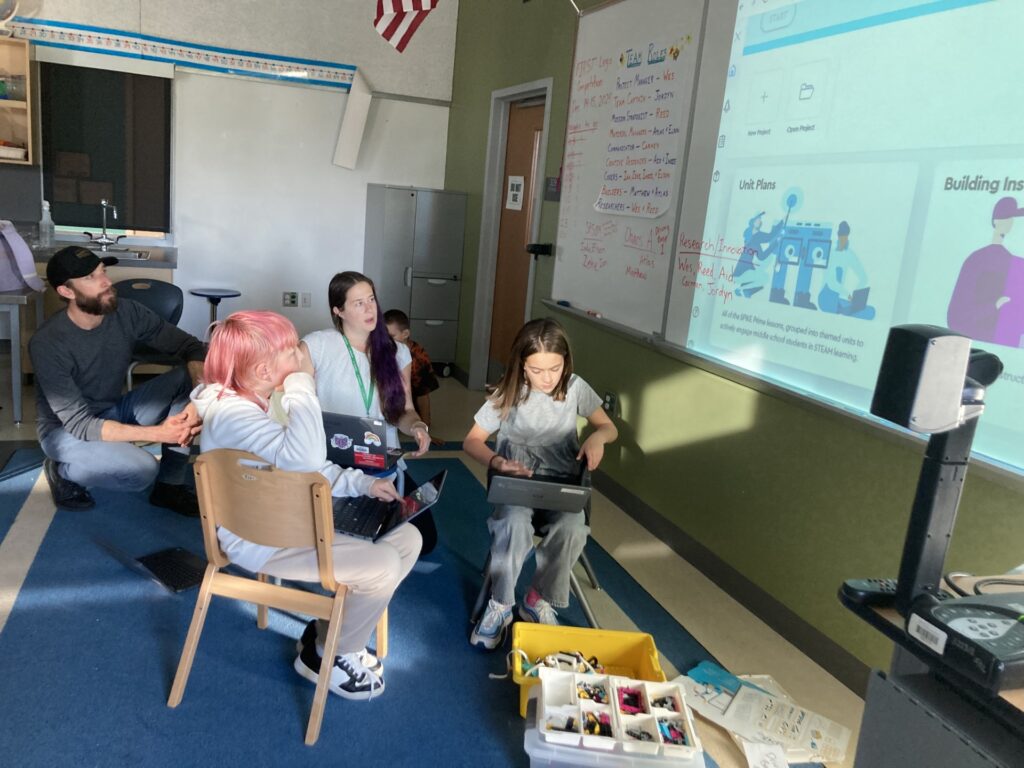 two students and two teachers working together on coding a robot for first lego robotics league. 