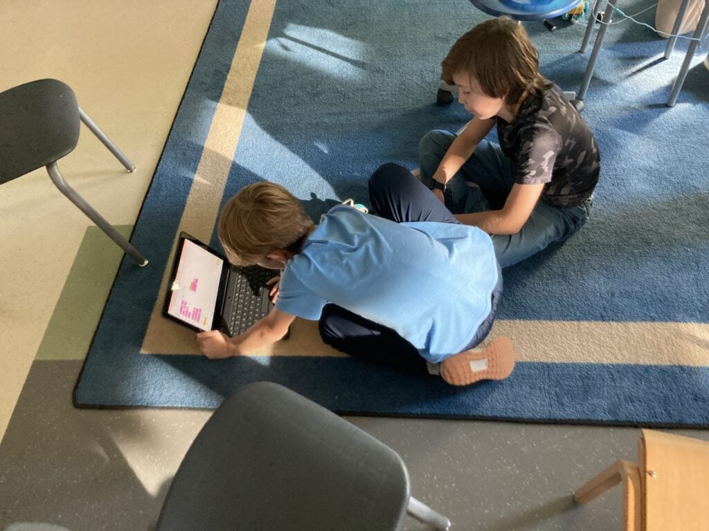 Students sitting on carpet and coding together for FLL team