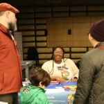 Two people and a child speak with an SPS staff member at the Admissions Fair