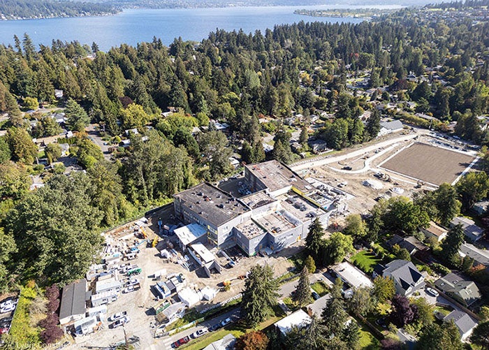 aerial of a building under construction with a square dirt field to the right