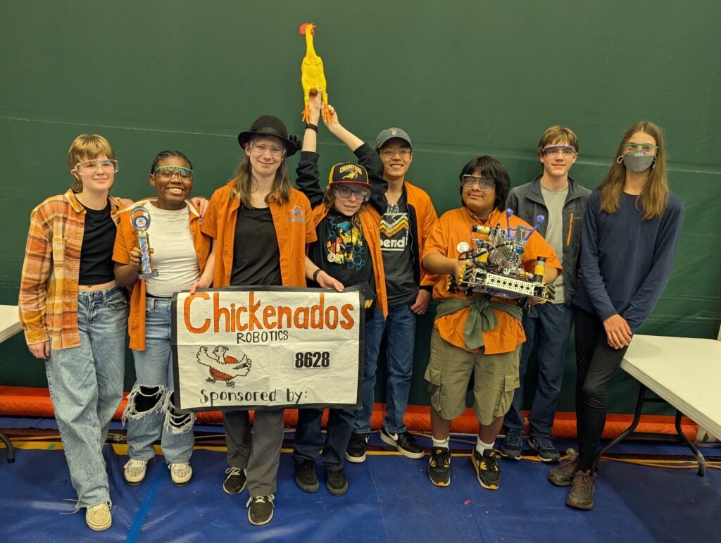 Students in front of homemade sign reading "Chickenados Robotics"