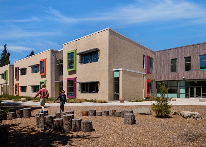 outdoor seating area with logs in front of a white brick building with colorful window frames