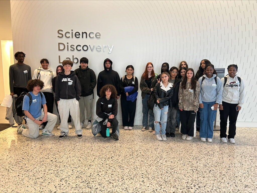 Studnets posing in front of white wall with Science Discover Lab  sign on it.