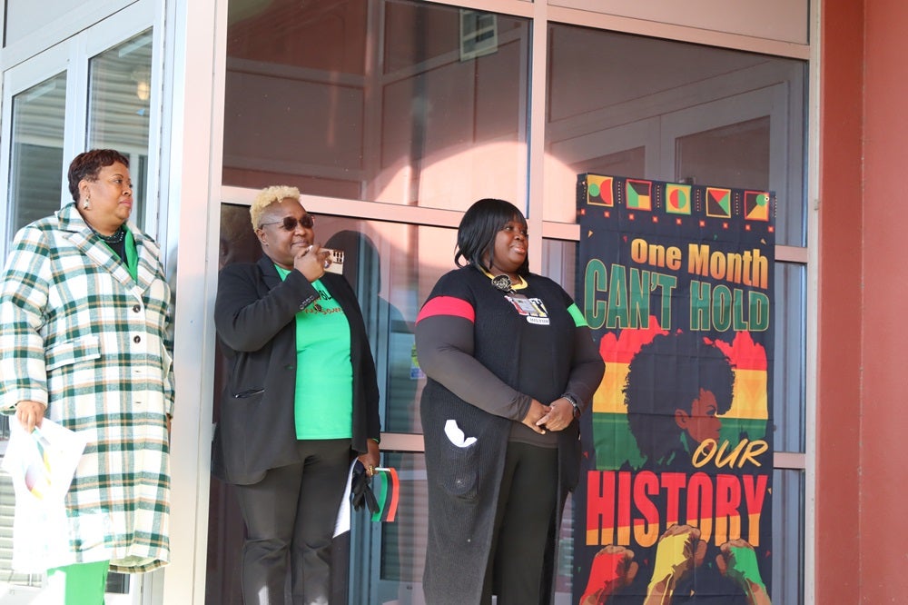 SPS staff members Bev Redmond, Anita Koyier-Mwamba, and Dr. Mia Williams watch the student speakers.