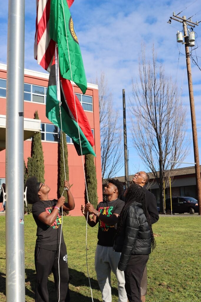 Rainier Beach High School’s Black student Union members Aida Starr, Oteko Mwamba and Akeem Murph raise the Pan-African flag