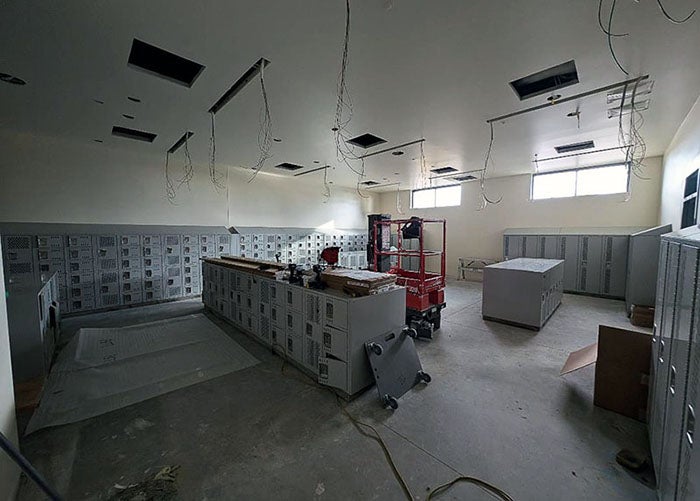 a room with wires for lights and banks of lockers being installed