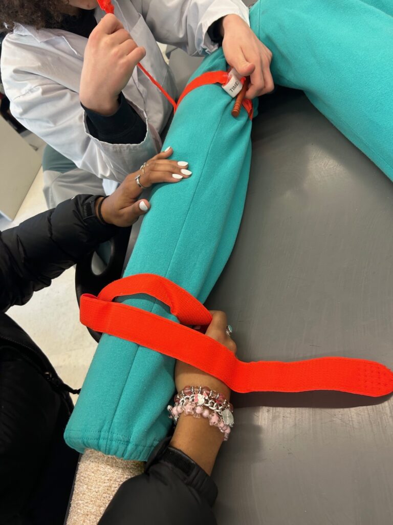 Students practicing tourniquet placement on a fake arm