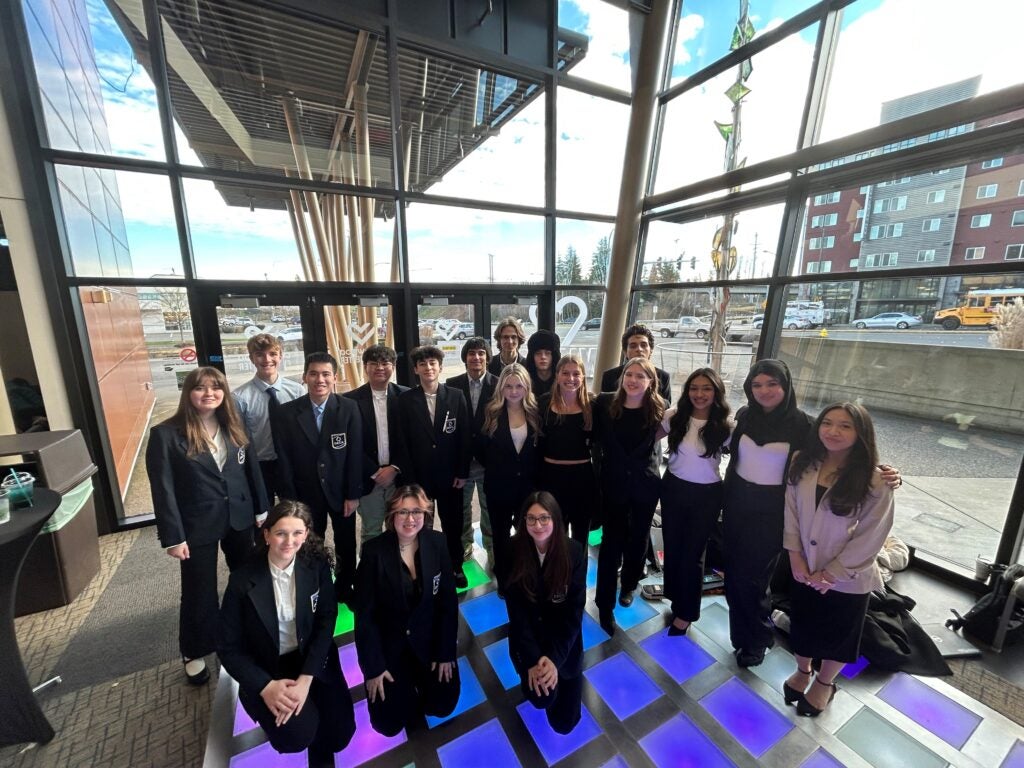 students posing in front of large window at competition