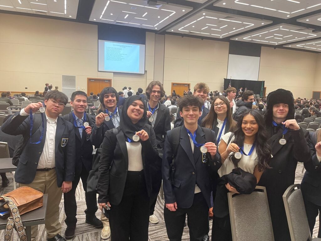 students in suits holding medals