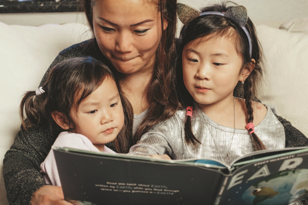 Parent reading a book to students