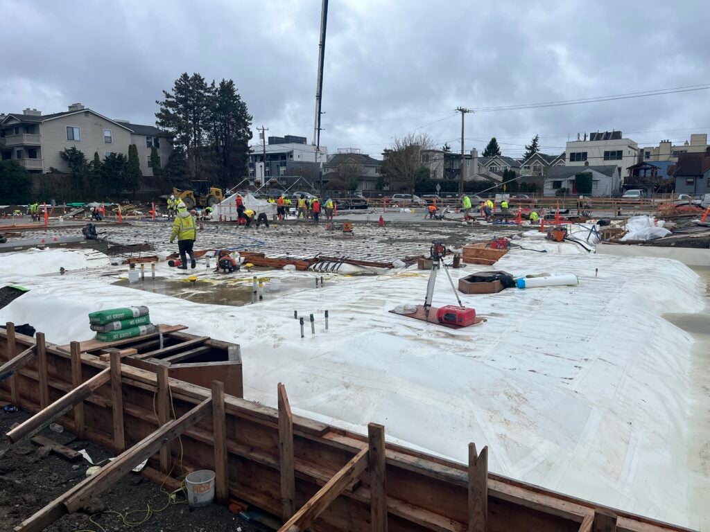 workers begin to spread concrete at a construction site