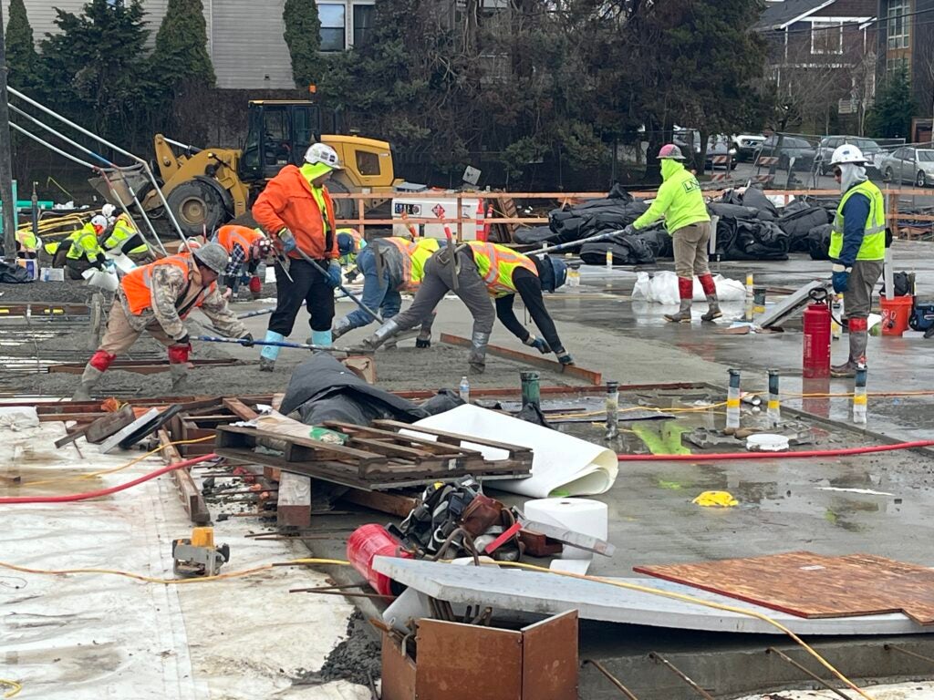 workers are spreading concrete at a construction site